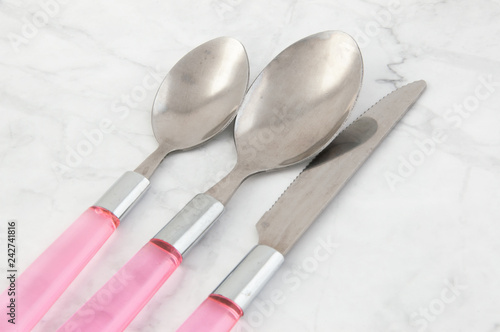Two spoons and knife on white gray background.