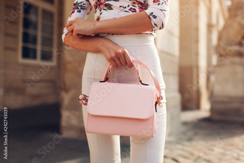 Close-up of stylish female handbag. Young woman wearing beautiful outfit and accessories outdoors. City fashion photo