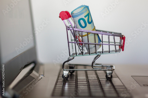 Shopping cart with banknotes on computer keyboard. Online shopping concept