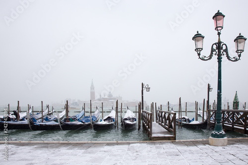 Snow on Venetian gondolas - snowing on St. Mark square, Venice, Italy, march 2018