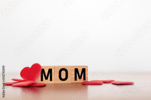 MOM word written on wooden cubes with red hearts around. Mother's day concept