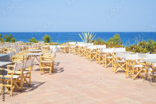Empty terrace with wooden chairs with sea view outdoors in Greece