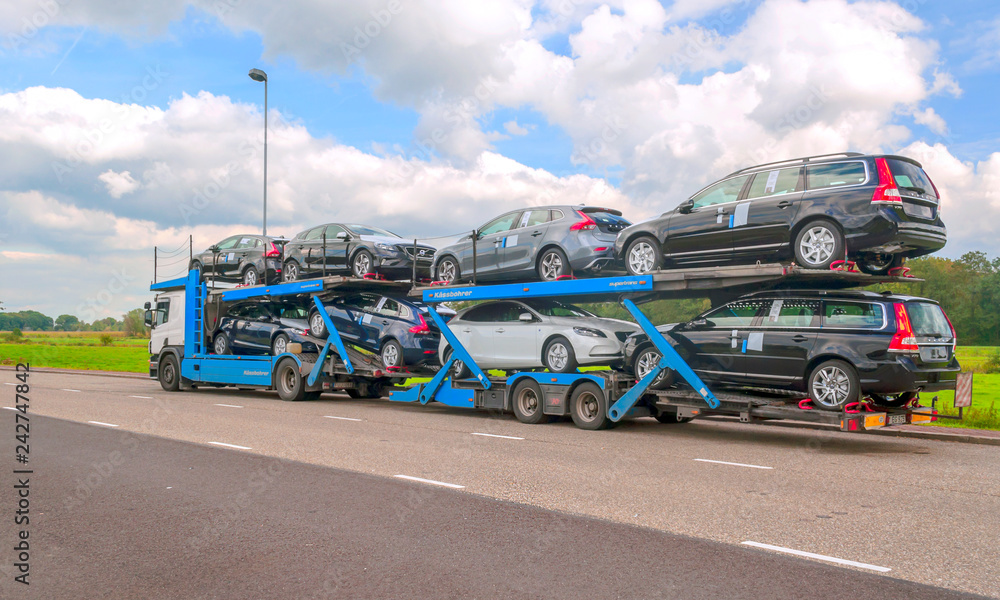 AMSTERDAM, HOLLAND-SEPTEMBER 2014. Truck trailer carrying several cars on a highway.