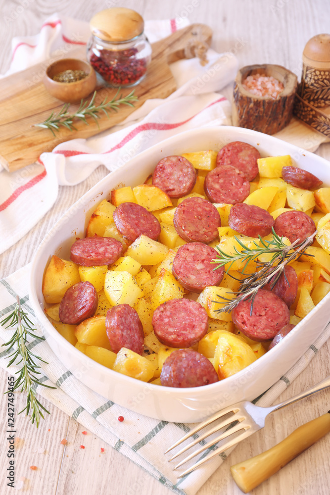 Fried potatoes with sausages and rosemary in ceramic bakeware Fried potatoes with sausages and rosemary in ceramic bakeware