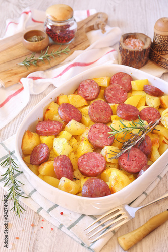 Fried potatoes with sausages and rosemary in ceramic bakeware