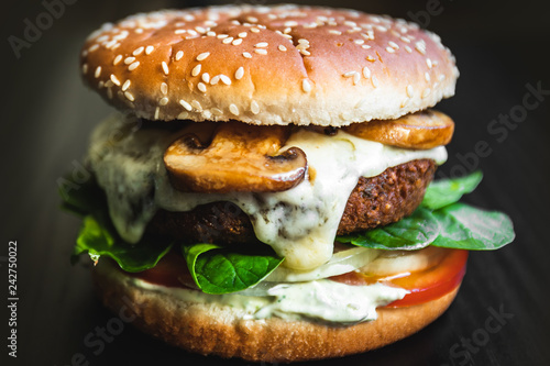 Hamburger vegetarian burger with falafel and vegetables salad tomato champignon and cheese tofu cheese all vegan food with nachos in blurred background