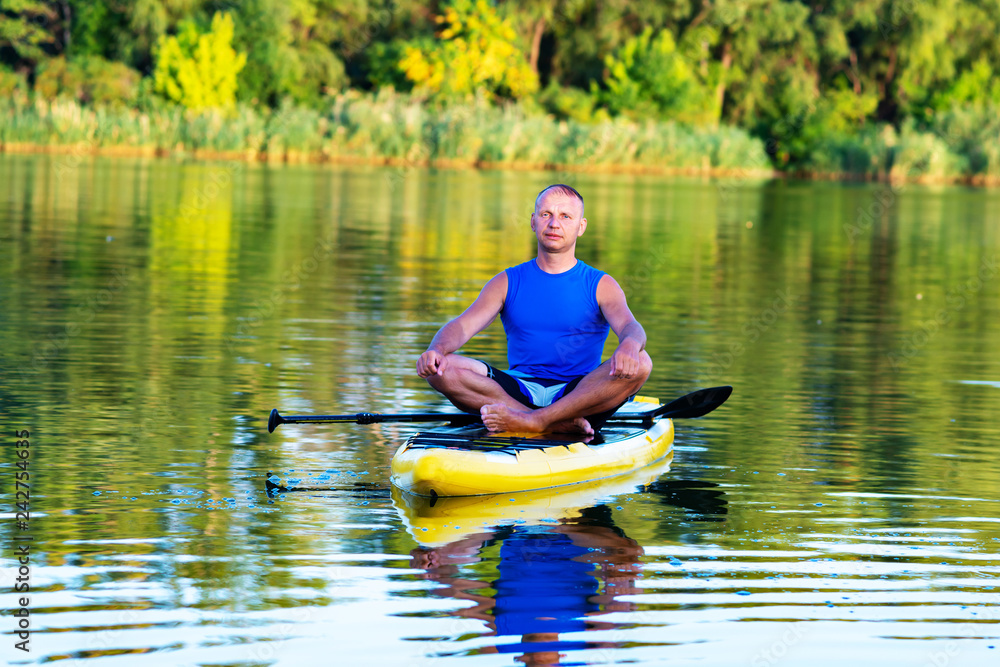 Man is relaxing and meditating on a SUP board Man is relaxing and meditating on a SUP board