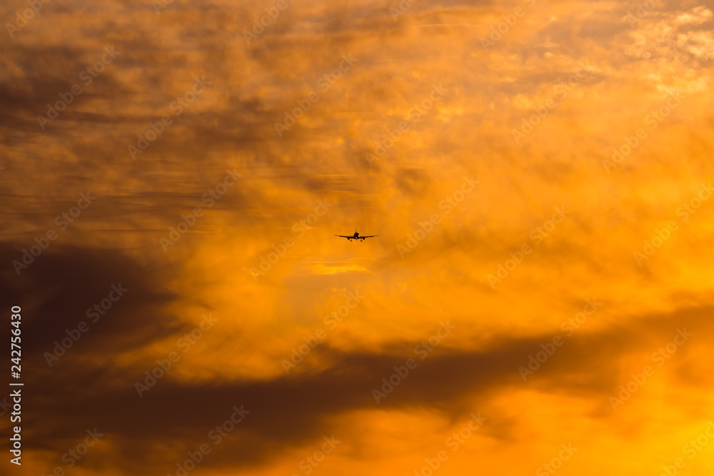 Airplane is landing during a nice cloudy sunrise.