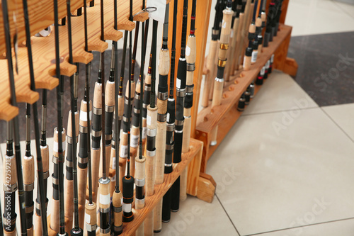 Stand with different fishing rods in sports shop, closeup