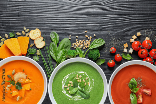 Flat lay composition with various soups and ingredients on wooden background. Healthy food