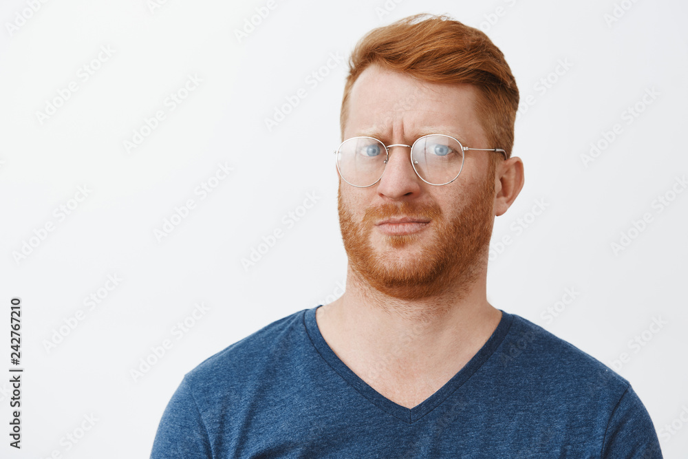 Headshot of confused and intense clueless handsome redhead guy with bristle in transparent glasses, pursing lips and frowning feeling questioned about what happening cannot understand Headshot of confused and intense clueless handsome redhead guy with bristle in transparent glasses, pursing lips and frowning feeling questioned about what happening cannot understand