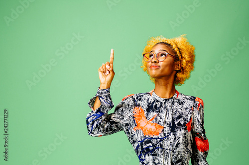 Young woman pointing up, isolated on green studio background. photo