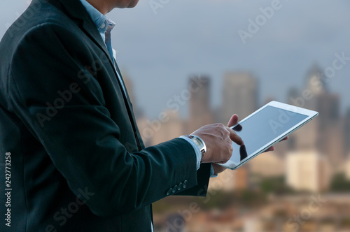 Business man working on media pad with business building background.
