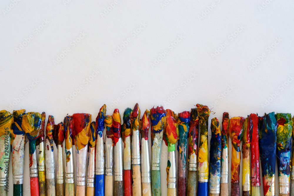 Artist Paintbrushes with Blank White Paper Lying on Wooden Table. Drawing Tools in Art Studio. Top View. Artist Paintbrushes with Blank White Paper Lying on Wooden Table. Drawing Tools in Art Studio. Top View.