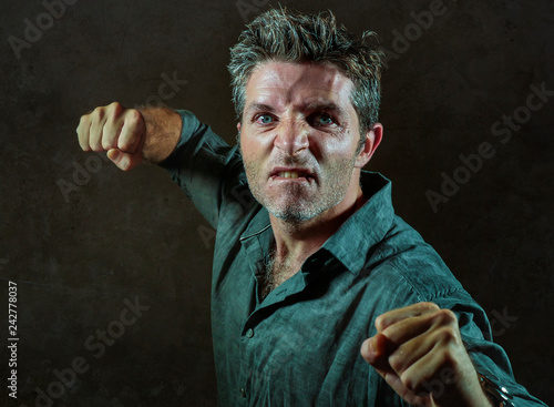 young upset and aggressive man in pub raising fist threatening throwing punch ready to fight as the violent thug troublemaker and furious wasted guy isolated on black photo