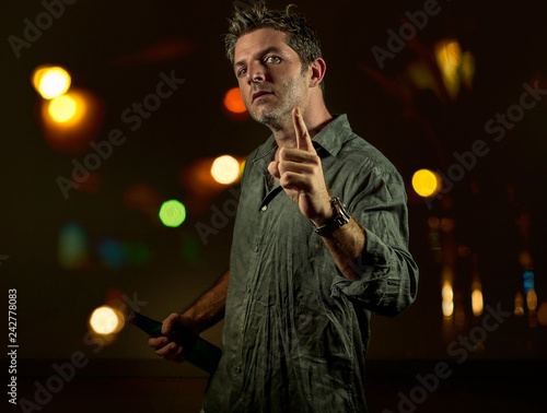 young upset and aggressive drunk man in pub at night holding beer bottle threatening ready to fight as the violent bar thug troublemaker and alcohol addict furious guy