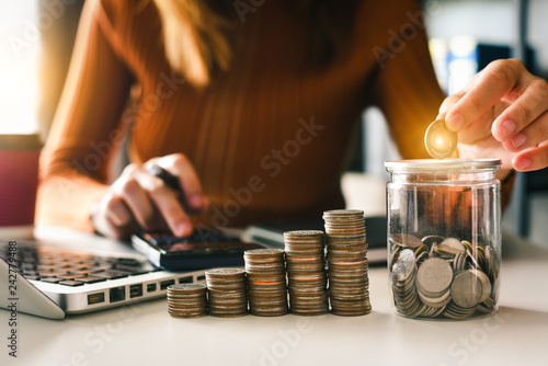 businesswoman holding coins putting in glass with using smartphone and calculator to calculate concept saving money for finance accounting