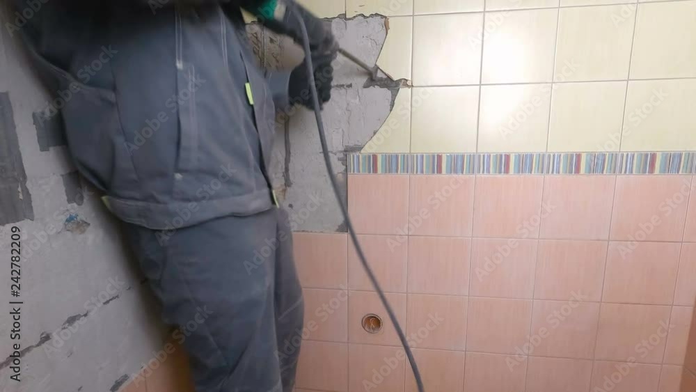 Demolition of old tiles with jackhammer. Renovation of old walls in the bathroom or kitchen