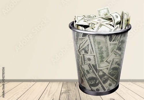 Money in thash bin on wooden floor photo