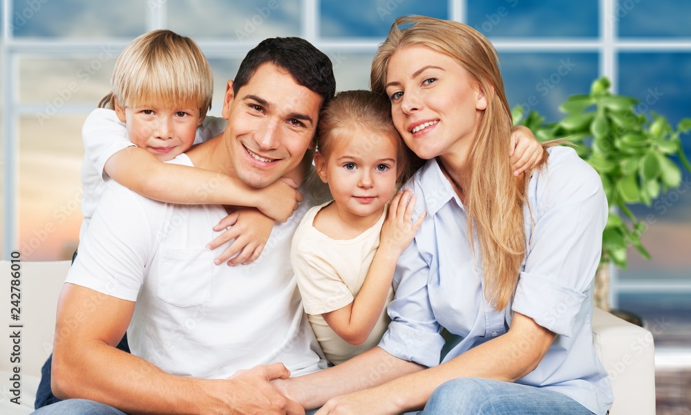 Beautiful smiling family sitting at sofa on room background Beautiful smiling family sitting at sofa on room background