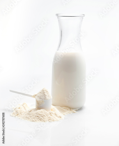 Bottle of fresh milk with powdered milk and spoon for baby on white background