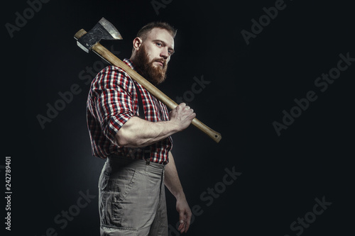 Fotografía Lumberjack brutal bearded man in red checkered shirt with a smoking tube and axe