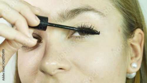 Close-up girl's eyes apply carcass on eyelashes, make-up in a professional beauty salon