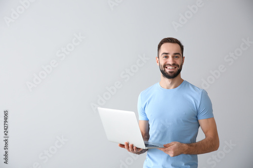 Young freelancer with laptop on light background photo