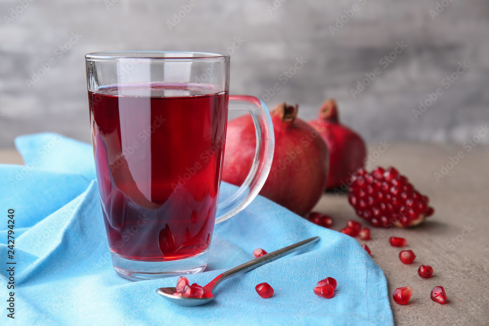 Glass cup of pomegranate juice on grey table Glass cup of pomegranate juice on grey table