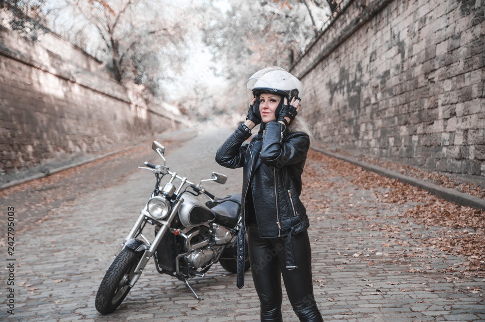 Beautiful biker woman posing outdoor with motorcycle.