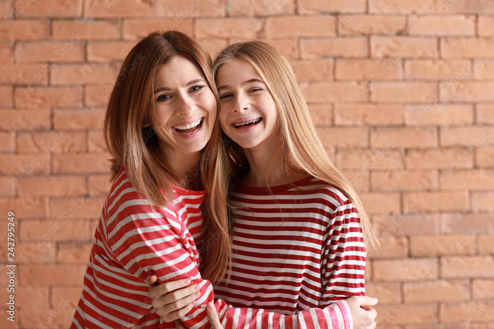 Portrait of happy mother and daughter on brick background Portrait of happy mother and daughter on brick background