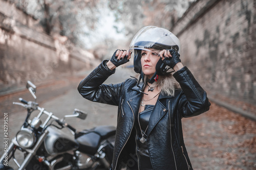 Beautiful biker woman posing outdoor with motorcycle.