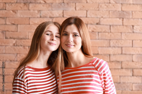 Portrait of happy mother and daughter on brick background