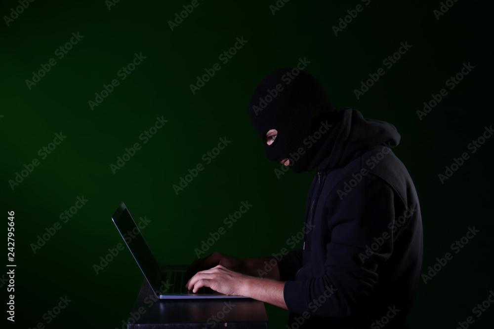 Professional hacker with laptop on dark background Professional hacker with laptop on dark background