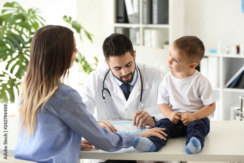 Fototapeta premium Young mother with her little son visiting doctor in clinic