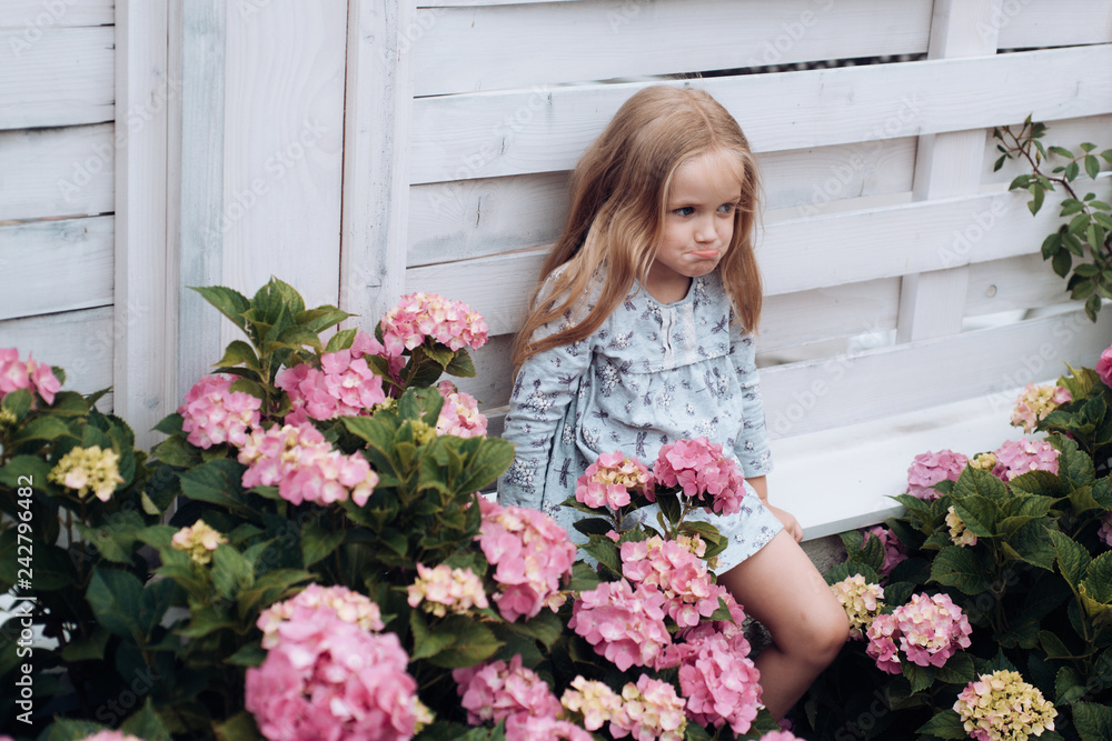 Little girl at blooming flower. Childrens day. Small baby girl. New life concept. Spring holiday. Summer. Mothers or womens day. Spring flowers. Childhood. Hot day