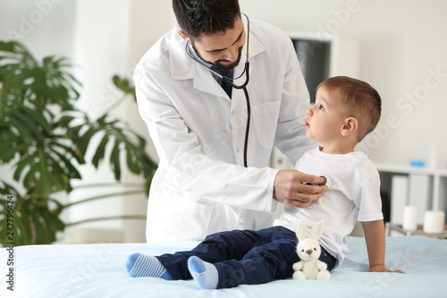 Male doctor working with cute little boy in clinic photo