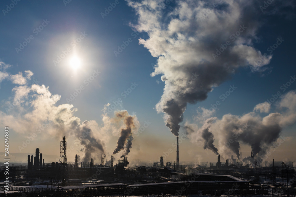 Industrial landscape. Heavy smoke from chimneys of an oil refinery at dawn. Image of factory smoke pollution, environmental problems and air pollution.