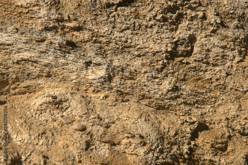 Brown sedimentary rock texture with contrasting shadows. Abstract background. Small stones and layers. Closeup.