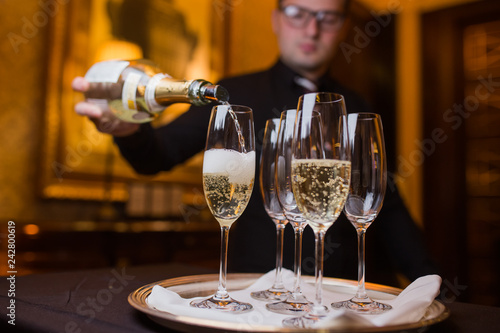 Waiter pouring champagne into glasses on a tray