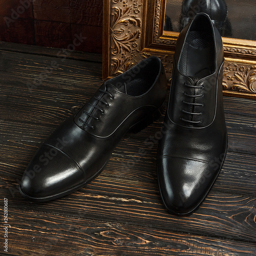 Black oxford shoes with golden picture frame on dark background