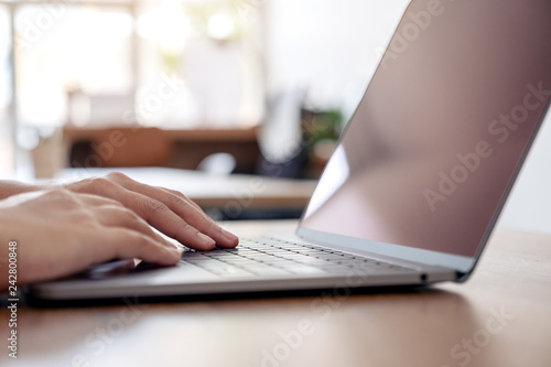 Closeup image of hands using and typing on laptop keyboard on the table