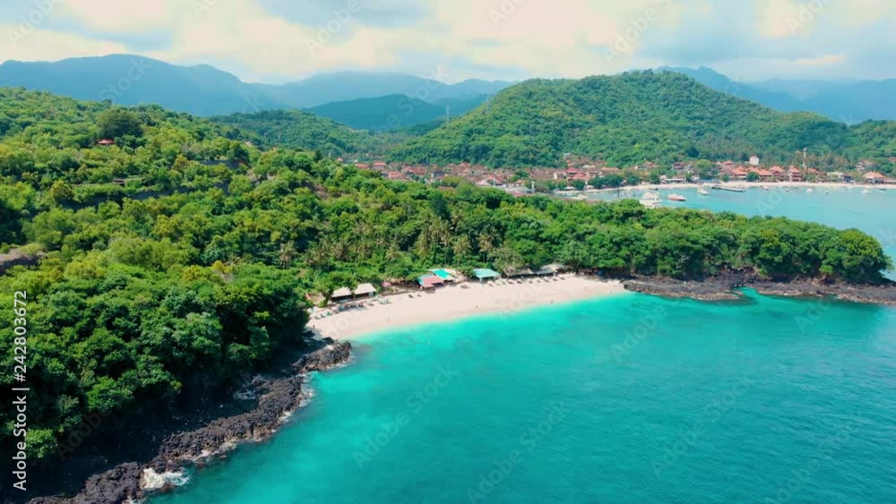 Aerial top view tropical paradise beach with small buildings, sun loungers and parasols in rainforest blue lagoon at Bali Island, Indonesia. top travel destination, best diving snorkeling. Aerial top view tropical paradise beach with small buildings, sun loungers and parasols in rainforest blue lagoon at Bali Island, Indonesia. top travel destination, best diving snorkeling.
