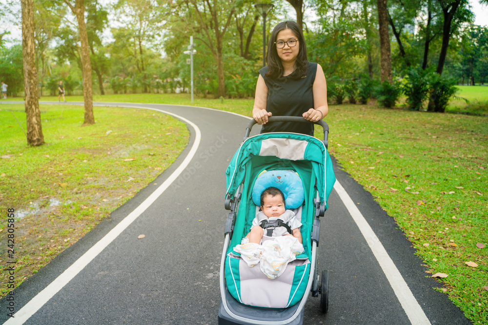 Mom walking in park with infant baby boy in stroller
