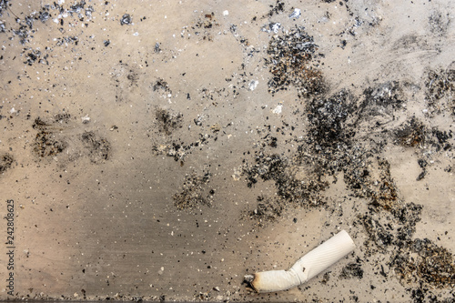 Close up cigarette and ash on the floor.
