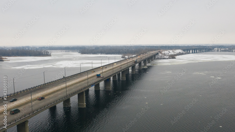 Naklejka premium Aerial top view on road bridge across the Dnieper River in Dnipro city at winter time. (Dnepr, Dnepropetrovsk, Dnipropetrovsk). Ukraine.