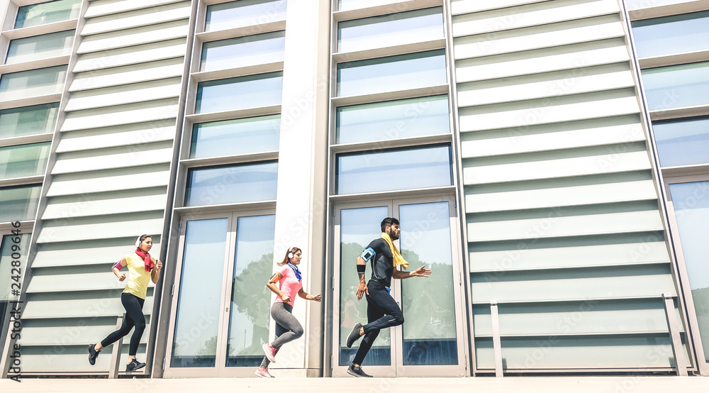 Fototapeta premium Young people running in modern urban area - Fitness girls running with male trainer coach in the city - Sport concept with friends group jogging in business center downtown on sunny day bright filter