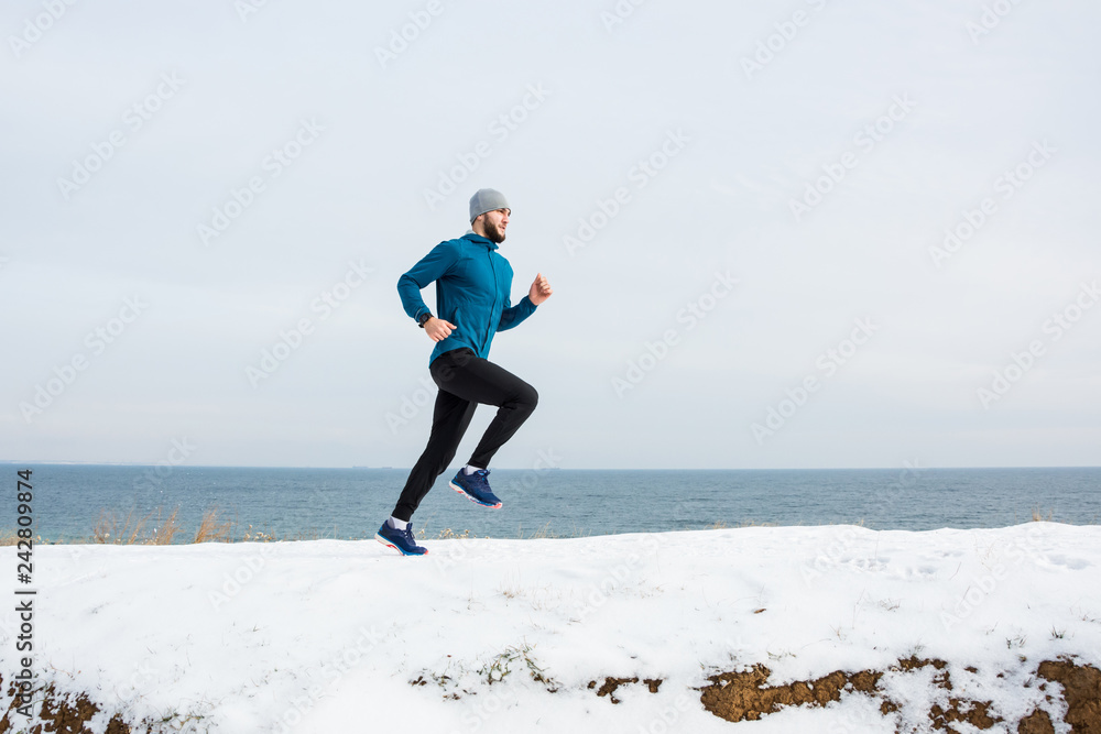Young male runner training outdoors in winter times, man run on the snow Young male runner training outdoors in winter times, man run on the snow