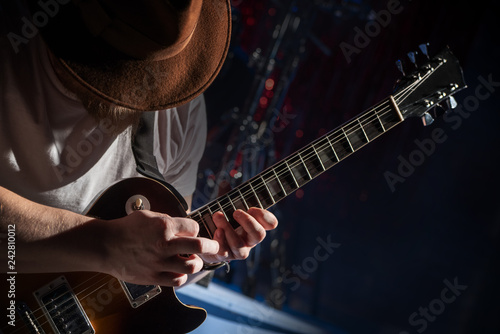 The guitarist in the hat plays solo on the electric guitar photo