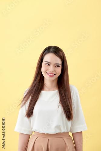 beautiful young woman with long black hair posing on yellow background